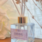 Clear diffuser bottle with gold cap labeled 'Lavendel' on a wooden surface.