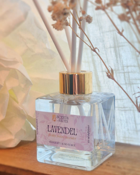 Clear diffuser bottle with gold cap labeled 'Lavendel' on a wooden surface.